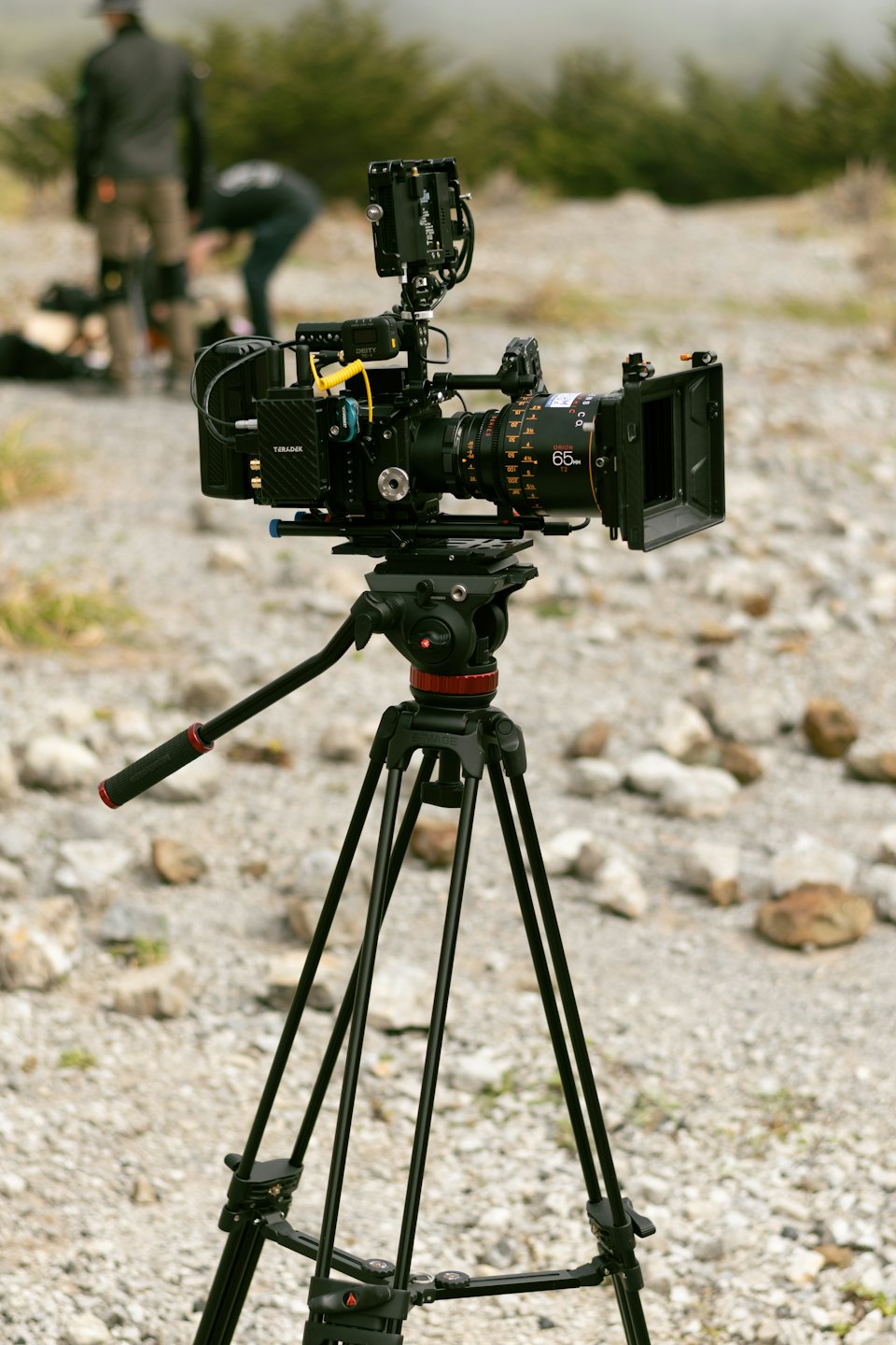 Videocamera professionale su treppiede in un terreno roccioso.